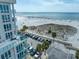 Aerial view of the beach with cars, palm trees, clear blue water and white sand at 15 Avalon St # 303, Clearwater Beach, FL 33767