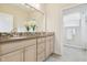 Bright bathroom featuring a double vanity, decorative mirror, and tiled walk-in shower at 16011 Bella Woods Dr, Tampa, FL 33647