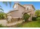 Side view of a two-story home showcasing the landscape, arched entryway and brick accents at 16011 Bella Woods Dr, Tampa, FL 33647