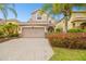 Charming two-story home with a brick driveway, lush landscaping, and a two-car garage at 16011 Bella Woods Dr, Tampa, FL 33647