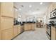 Bright kitchen boasts stainless steel appliances, tile flooring, light wood cabinetry, and black countertops at 16011 Bella Woods Dr, Tampa, FL 33647
