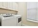 Laundry room with white washer and dryer, and white cabinets for storage space at 16011 Bella Woods Dr, Tampa, FL 33647