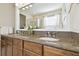 Main bathroom vanity with granite counters, double sinks, wood cabinets, and decorative mirror at 16011 Bella Woods Dr, Tampa, FL 33647