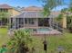 Backyard view of a screened-in pool surrounded by brick pavers and tropical landscaping at 16011 Bella Woods Dr, Tampa, FL 33647