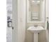 Neutral powder room with pedestal sink, medicine cabinet, and decorative mirror with kitchen view at 16011 Bella Woods Dr, Tampa, FL 33647