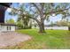 Large backyard with mature tree, brick patio, and white privacy fence at 1881 Oak Park N Dr, Clearwater, FL 33764