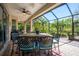 A covered patio featuring a ceiling fan, a dining table with seating, and a screened enclosure overlooking lush greenery at 309 Royal Bonnet Dr, Apollo Beach, FL 33572