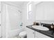 Bright bathroom featuring a shower-tub combo, a sleek vanity with dark countertop, and neutral tile flooring at 3115 W Paxton Ave, Tampa, FL 33611