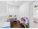 Bright bedroom area featuring hardwood floors, white walls, a desk, and view of a bedroom with a ceiling fan at 3115 W Paxton Ave, Tampa, FL 33611