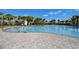 Beautiful outdoor swimming pool with chairs and umbrellas, surrounded by palm trees, in a stunning community at 3139 Marine Grass Dr, Wimauma, FL 33598