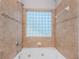 A tiled bathroom featuring a large tub with jets and a glass block window at 409 S Arrawana Ave, Tampa, FL 33609