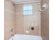 A full bathtub is tiled with decorative tiling and a window at 409 S Arrawana Ave, Tampa, FL 33609