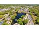 An aerial view of condos around a tranquil lake with a fountain, lush green landscaping, and nearby shopping centers at 4160 Pinelake Ln # 201, Tampa, FL 33618