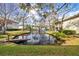 Relaxing pond view featuring condos with a wooden dock, enhanced by lush greenery and a soothing water fountain at 4160 Pinelake Ln # 201, Tampa, FL 33618