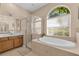 Elegant bathroom featuring a soaking tub, glass-enclosed shower, and double sinks with wooden cabinetry at 4315 70Th E Ave, Ellenton, FL 34222