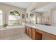 Luxurious bathroom featuring a soaking tub, separate shower, double sinks, and natural light from arched windows at 4315 70Th E Ave, Ellenton, FL 34222