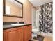 Bathroom with wood cabinets, a framed mirror, and a shower with a tub and patterned shower curtain at 5831 Leopardstown Dr, Tampa, FL 33610
