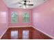 This bedroom features hardwood floors, two windows, a ceiling fan and a pink painted walls at 5831 Leopardstown Dr, Tampa, FL 33610