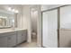 Modern bathroom features a glass shower, gray cabinets, a white countertop, and neutral tiles at 8521 Dove Bog Ter, Parrish, FL 34219