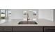 Kitchen island featuring a stainless steel sink, faucet, quartz countertops, and gray cabinetry at 8521 Dove Bog Ter, Parrish, FL 34219