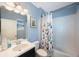 Stylish bathroom with a plant-themed shower curtain, clean white tiles, and blue walls at 8890 Arabella Ln, Seminole, FL 33777