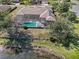 Aerial view of the home with a screened pool, surrounded by mature trees and a well-maintained landscape at 10084 Twelve Oaks Ct, Weeki Wachee, FL 34613