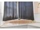 Close-up of a peach-colored bathtub with gray curtains, with a bright window at 10084 Twelve Oaks Ct, Weeki Wachee, FL 34613