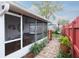 Backyard featuring a screened sunroom, brick pathway, and lush landscaping at 1016 Greenleaf Way, Tarpon Springs, FL 34689