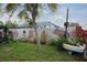 Landscaped backyard featuring a painted brick wall, boat decor, and view of the screened pool at 1016 Greenleaf Way, Tarpon Springs, FL 34689