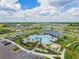 An aerial view of the community pool, parking lot, and surrounding homes with well-manicured landscaping and roadways at 10741 Charlotte Dr, Parrish, FL 34219