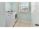 Bright laundry room features a window, laundry machines, tile flooring and blue walls at 10741 Charlotte Dr, Parrish, FL 34219