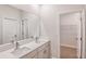 Bright bathroom with double vanity, quartz countertops, framed mirror, and access to walk-in closet at 12160 Cattleside Dr, Riverview, FL 33579