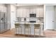 Stylish kitchen with white cabinets, stainless steel appliances, island with breakfast bar, and wood floors at 12160 Cattleside Dr, Riverview, FL 33579