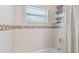Close up of a tub and shower combo with decorative mosaic tile and a shower caddy at 1221 Dustin Rd, North Port, FL 34288