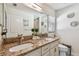 Bathroom featuring dual sinks with granite countertops and white cabinets and custom mirrors at 1221 Dustin Rd, North Port, FL 34288