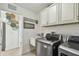 Bright laundry room featuring stainless steel washer/dryer, utility sink, and overhead cabinets at 1221 Dustin Rd, North Port, FL 34288