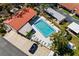 Aerial view of a community pool, a parking lot, and buildings with red tile roofs at 1366 Carlisle Ct, Dunedin, FL 34698