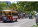 Vibrant street scene featuring a trolley, shops, palm trees, and pedestrian activity at 1366 Carlisle Ct, Dunedin, FL 34698