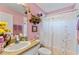 Charming bathroom with pink walls, decorative shelves, and a shower with a floral curtain at 19826 Wyndham Lakes Dr, Odessa, FL 33556