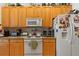 Practical kitchen with wooden cabinets, white appliances including a microwave, toaster oven, and refrigerator with magnets at 19826 Wyndham Lakes Dr, Odessa, FL 33556
