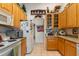 Well-lit kitchen with wooden cabinets, white appliances, and a view into the hallway, decorated with Americana at 19826 Wyndham Lakes Dr, Odessa, FL 33556