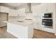 Bright kitchen features white cabinets, stainless steel appliances, and a center island with sink and quartz countertops at 1988 Webbstone Way, Zephyrhills, FL 33541