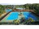 Blue tennis courts surrounded by fence and palm trees, adjacent to a community clubhouse and swimming pool at 20151 Bay Cedar Ave, Tampa, FL 33647