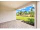Covered back patio features brick pavers, a well manicured yard, and a view of lush landscaping at 20387 Symphony Pl, Venice, FL 34293