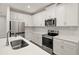 Well-lit kitchen featuring stainless appliances, shaker cabinets, quartz countertop and wood look tile flooring at 20405 Symphony Pl, Venice, FL 34293