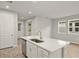 Modern kitchen island with stainless steel sink, white cabinets, quartz countertop, and wood look tile flooring at 20405 Symphony Pl, Venice, FL 34293