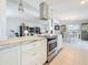 Open kitchen with stainless steel hood, marble island, and view of the living and dining areas at 2593 W Vina Del Mar Blvd, St Pete Beach, FL 33706