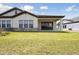 Rear exterior of home featuring covered patio and grassy lawn at 35587 Stableton Ln, Zephyrhills, FL 33541