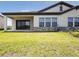 Backyard patio with a covered porch, sliding glass doors, and landscaped yard at 35593 Stableton Ln, Zephyrhills, FL 33541