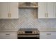 Close up of modern kitchen features white cabinets, stainless steel range hood, and herringbone backsplash at 4154 Sinclair Pl, Land O Lakes, FL 34639